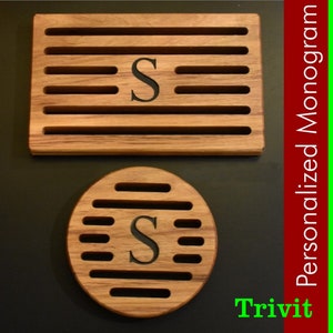 May include: Two wooden coasters with a slatted design. The larger coaster is rectangular and the smaller coaster is round. Both coasters have the letter "S" engraved in the center. The coasters are made by Trivit and are personalized with a monogram.