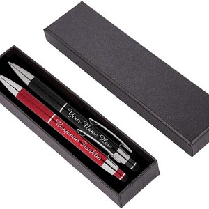 May include: Two pens in a black box. One pen is black with the text "Your Name Here" and the other pen is red with the text "Benjamin Franklin".
