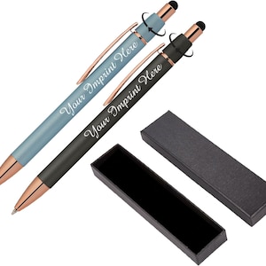 May include: Two twist-action ballpoint pens with stylus tips, one light blue and one black, both featuring rose gold accents and clips. Each pen is engraved with the text Your Imprint Here. A black rectangular gift box with a lid is included.