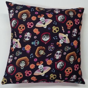 May include: A black pillowcase with a colorful pattern of characters from the movie Coco. The pattern includes skeletons, flowers, and musical notes.