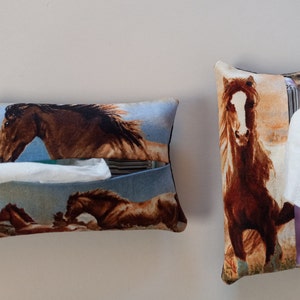 May include: Two brown and white horse print tissue box covers. One is lying flat and the other is standing upright. Both have a blue background and a white tissue peeking out.