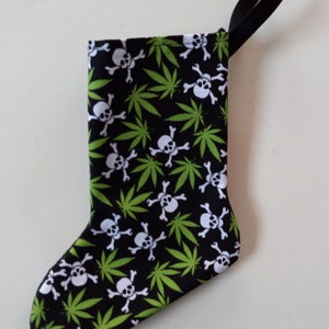 May include: A black Christmas stocking with a green marijuana leaf and white skull pattern.