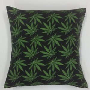 May include: A black and green throw pillow with a repeating pattern of marijuana leaves.