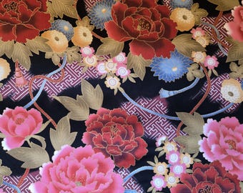 May include: A fabric with a black background featuring a floral pattern. The design includes large red and pink peonies, blue and yellow flowers, and gold-colored leaves. Decorative rope and geometric shapes are also present.