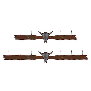 May include: Two rustic brown metal wall hooks with a stylized bull skull design in the center. Each hook has six hooks for hanging items.
