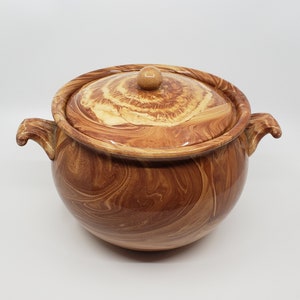 May include: A brown ceramic pot with a lid, featuring a marbled swirl pattern. The pot has two handles and a knob on the lid.