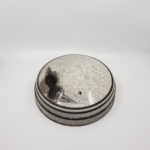 May include: White ceramic lid with a black floral design and a crackled glaze. The lid has a small hole in the center.