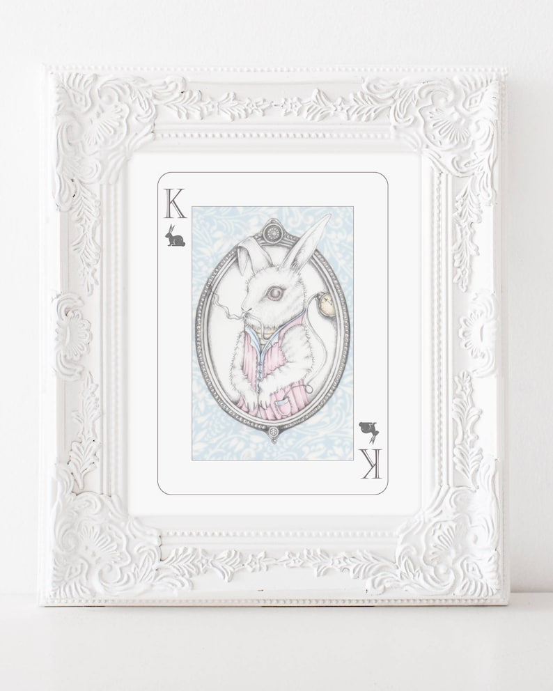 May include: A white rabbit wearing a pink and white striped shirt and a pocket watch, holding a cigarette. The rabbit is depicted on a playing card with the letter 'K' in the corner. The card has a blue and white background with a floral pattern.