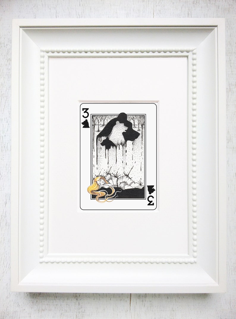 Pu&ograve; includere: Un'illustrazione in bianco e nero di una carta da gioco, il tre di picche. La carta rappresenta una donna sdraiata a terra con una testa d'orso sopra di lei. La testa dell'orso gocciola un liquido nero.