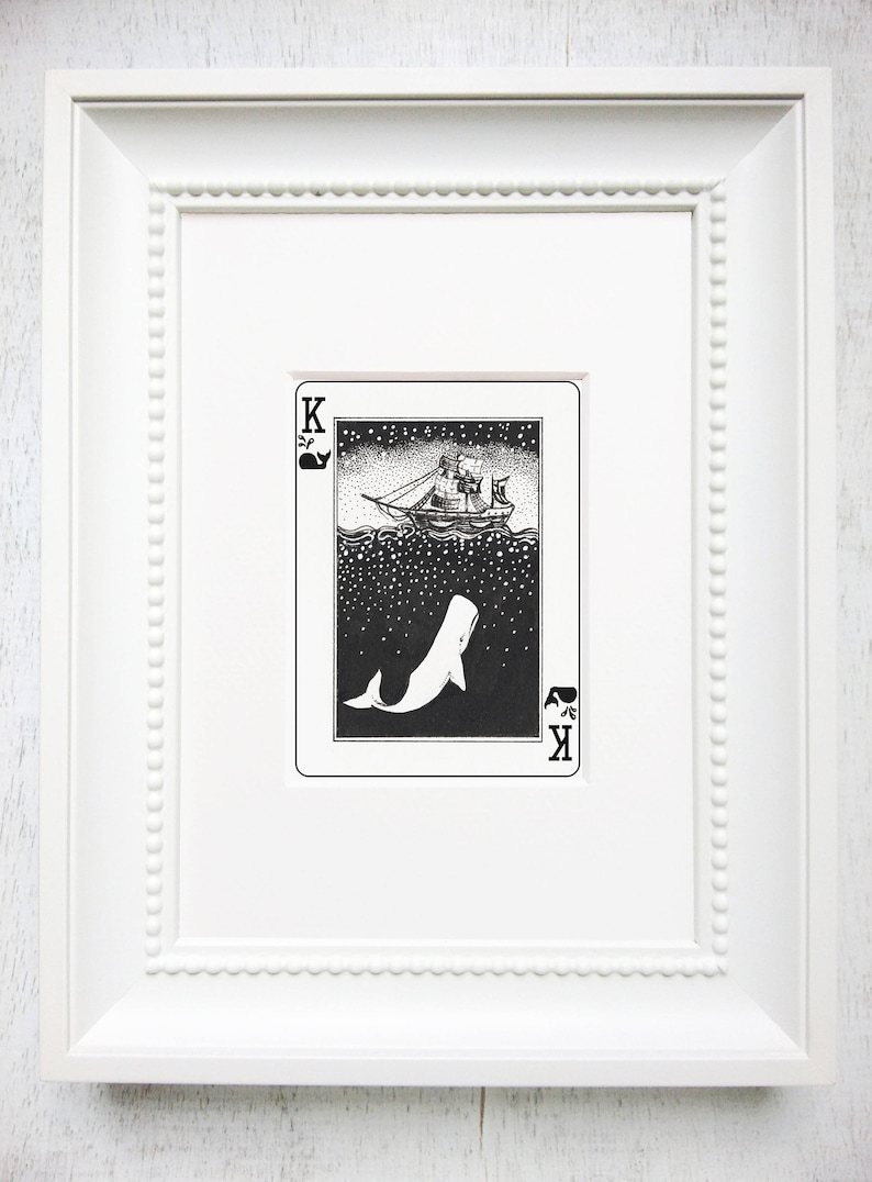 May include: A black and white illustration of a whale and a ship on a playing card. The card is a King of Spades and features a whale breaching the surface of the water with a ship sailing above. The card is framed in a white frame.