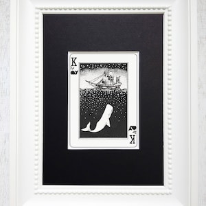 May include: A black and white illustration of a playing card depicting a whale and a ship. The card is a King of Spades and has a black background with white stars. The whale is swimming upwards towards the ship, which is sailing on the surface of the water.