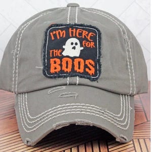May include: Gray distressed baseball cap with a black and orange patch that says "I'm here for the boos" with a white ghost in the middle.