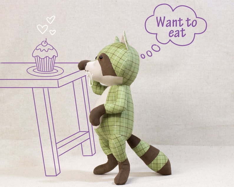 Puede incluir: Un juguete de peluche de mapache de cuadros verde y marr&oacute;n con una cola marr&oacute;n, mirando un cupcake con una cereza en la parte superior. El mapache tiene un globo de pensamiento sobre su cabeza que dice "Quiero comer".