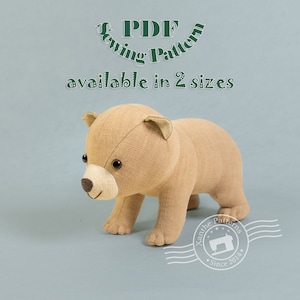 Peut inclure: Un ourson en peluche marron avec des yeux noirs et un sourire cousu. L'ourson est debout sur un fond bleu clair avec le texte "PDF Sewing Pattern available in 2 sizes" et un tampon blanc avec le texte "Xanthe Patterns Since 2014".