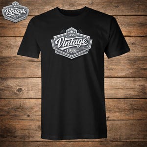 Peut inclure: T-shirt noir avec un motif blanc et gris "Vintage 1986+". Le design rétro comprend des étoiles et une forme de bouclier. Idéal pour un look décontracté. Le t-shirt est en matière souple.