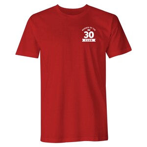 Puede incluir: Camiseta roja de manga corta con un gr&aacute;fico blanco que dice "Member of the 30 Club" con una corona sobre el n&uacute;mero 30.