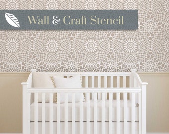 May include: A white crib with a white ruffle skirt and a white wall behind it. The wall has a stencil design of a repeating pattern of circles.