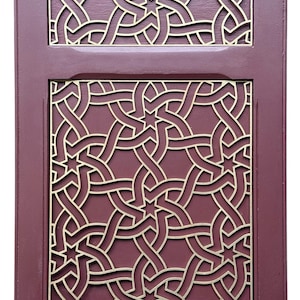 May include: A rectangular wooden panel with a burgundy frame and intricate gold-colored geometric patterns. The design features interwoven lines and star-shaped elements, creating a decorative and ornate appearance. The panel is divided into two sections.