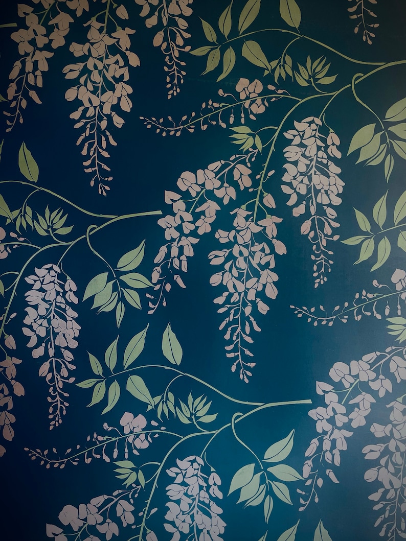 Pu&ograve; includere: Uno sfondo blu-verde con un motivo ripetitivo di fiori di glicine bianchi e foglie verdi.