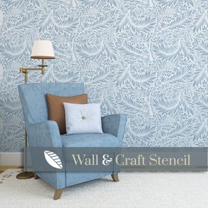 May include: A blue armchair with brown and light blue pillows sits in front of a wall with a blue and white floral stencil pattern. The text "Wall & Craft Stencil" is at the bottom of the image.