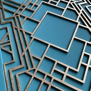 May include: A silver geometric design on a blue background. The design is made up of overlapping squares and rectangles, creating a complex pattern.