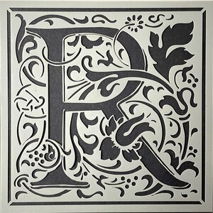 May include: A square stencil featuring the letter "R" in a decorative, ornate font. The letter is white, with a dark gray background. The design includes floral and vine-like elements, creating a vintage or antique aesthetic. The stencil is suitable for crafts and DIY projects.