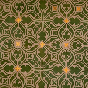 Może przedstawiać: Powtarzający się wzór z symetrycznym wzorem z zielonymi i złotymi akcentami. Wzór zawiera stylizowane kształty kwiatowe i geometryczne, ze złotymi elementami w kształcie gwiazd. Tło jest w neutralnym beżowym kolorze.
