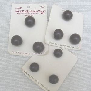 May include: Three white cardboard cards holding dark brown spherical buttons. The cards feature the text Lansing A Great Name in Buttons, Washable, and model numbers including NO. 8742 SZ. 28-3/4 inch and NO. 8742 SZ. 22-7/8 inch printed in black ink.