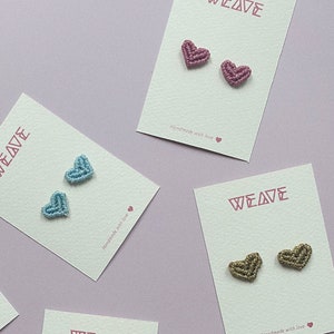 Può includere: Cinque carte con la parola "WEAVE" stampata su di esse. Ogni carta presenta un paio di piccoli orecchini a forma di cuore realizzati con corda colorata. Gli orecchini sono di colore blu, nero, rosa, bordeaux e marrone.