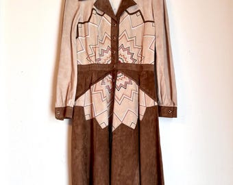 Könnte beinhalten: Ein langärmeliges braunes Wildlederkleid mit einem geometrischen Muster in Braun-, Rosa- und Weißtönen. Das Kleid hat einen Knopfleisten vorne und einen Kragen.