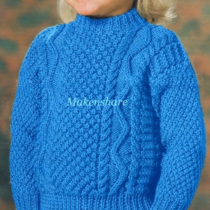 Op de afbeelding: Een blauwe gebreide trui met een kabelbreipatroon. De trui heeft een hoge hals en lange mouwen.