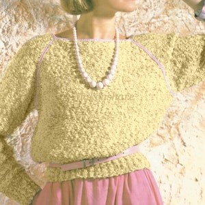 May include: A pale yellow knitted sweater with a pink trim around the neckline and sleeves. The sweater has a relaxed fit and a slightly scooped neckline. The model is wearing a pearl necklace and a pink belt.
