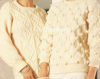 Könnte beinhalten: Zwei cremefarbene Strickpullover mit unterschiedlichen Mustern. Ein Pullover hat ein Zopfmuster und der andere ein Noppenmuster.