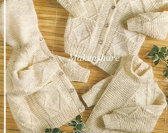 Könnte beinhalten: Drei Strickpullover in Cremefarbe. Die Pullover haben ein Rautenmuster und liegen auf einer gewebten Bambusoberfläche.
