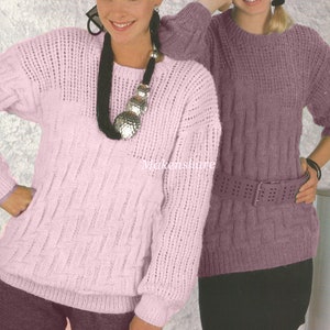 Puede incluir: Dos suéteres de punto, uno rosa y otro morado, con un patrón de punto de cable. El suéter rosa tiene un delicado diseño de calado en las mangas y el escote.