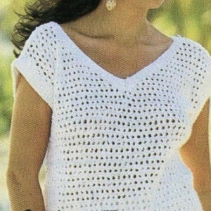 May include: White crochet top with a v-neck and short sleeves. The top is made of a lightweight, open-weave fabric.