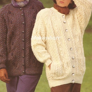 May include: Two knitted cardigans, one brown and one cream, with a cable knit pattern and button fastenings. The cardigans are shown on two people standing in a field.