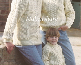 Könnte beinhalten: Drei cremefarbene Strickpullover mit Zopfmuster, einer für jedes Familienmitglied. Die Pullover haben ein traditionelles irisches Design mit einem strukturierten Muster. Die Pullover werden von einem Mann, einer Frau und einem Kind getragen.
