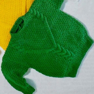 May include: A green knitted sweater with a cable knit pattern. The sweater has a crew neck and long sleeves.