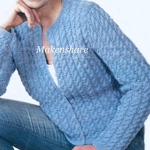 May include: A light blue knitted cardigan with a textured pattern. The long-sleeved sweater has a round neckline and a buttonless front. The word "Makenshare" is printed on the cardigan. The cardigan is worn with blue jeans.