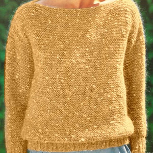 May include: A mustard-colored knit sweater with a wide neckline. The sweater has a textured appearance with small, lighter-colored flecks throughout the fabric. The cuffs and hem are ribbed, and the overall style is casual and comfortable.