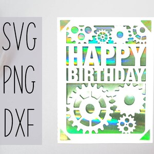 May include: White card with a holographic background and a cut-out design of gears and the words "Happy Birthday".
