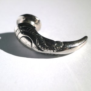 May include: A silver claw-shaped earring with intricate details.