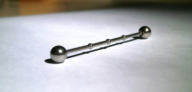 May include: A silver barbell with two round balls on either end. The barbell has a smooth, polished finish.