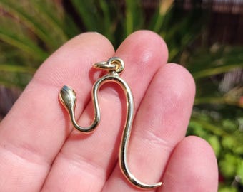 Op de afbeelding: Een gouden slangenhanger. De slang is in de vorm van een 'S' gekruld.