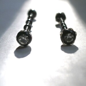 May include: Two black barbell earrings with clear crystal stones.