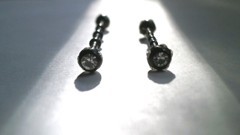 May include: Two black barbell earrings with clear crystal stones.