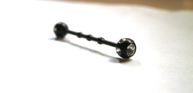 May include: Black barbell with clear crystal accents on each end.