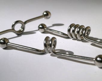 May include: Three silver barbell piercings with different styles of ends. One has a circular end, one has a spiral end, and one has a straight end.