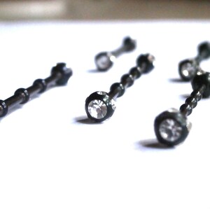 May include: Five black barbell body jewellery pieces with clear crystal accents.